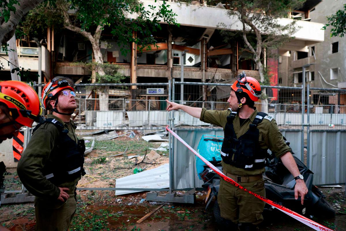 A rescuer worker gestures near a damaged building in the Israeli city of Tel Aviv following an Iranian missile attack on June 16, 2025. Israel’s Magen David Adom emergency service said on June 16 that three people were killed and 74 wounded following Iran’s latest missile attack.