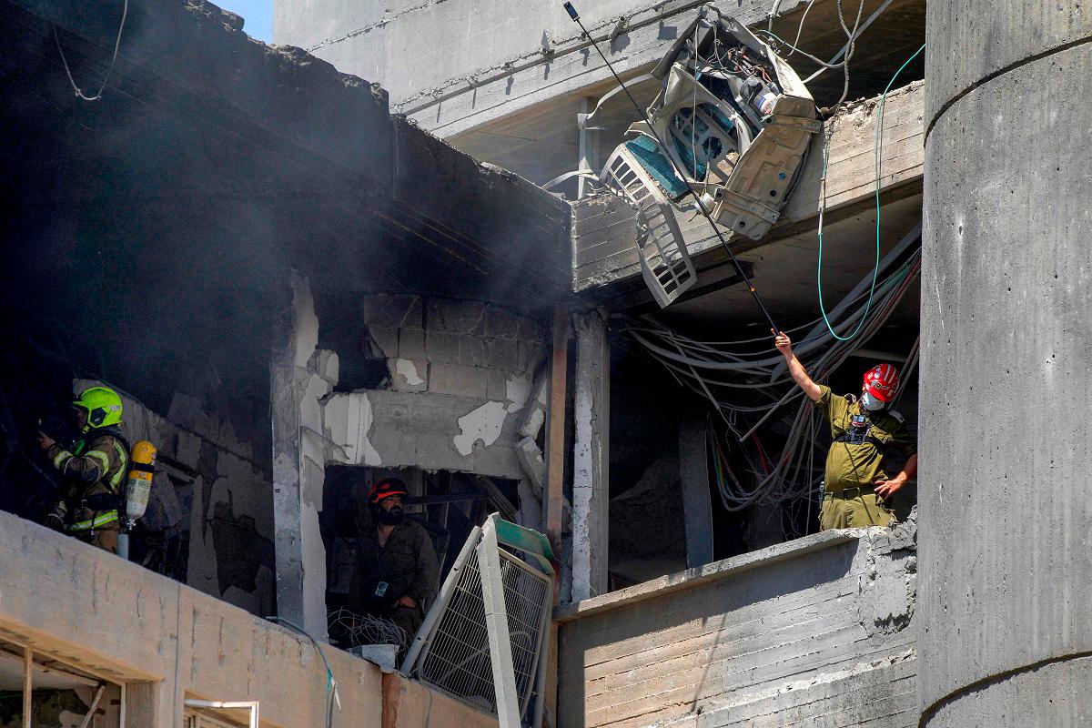 First responders inspect a heavily-damaged building at Soroka Hospital in Beersheba in southern Israel following an Iranian missile attack on June 19, 2025. A hospital in southern Israel was hit during a barrage of “dozens” of Iranian missiles on June 19, officials said, while another impact was reported by emergency services in the Tel Aviv area. - MAYA LEVIN / AFP