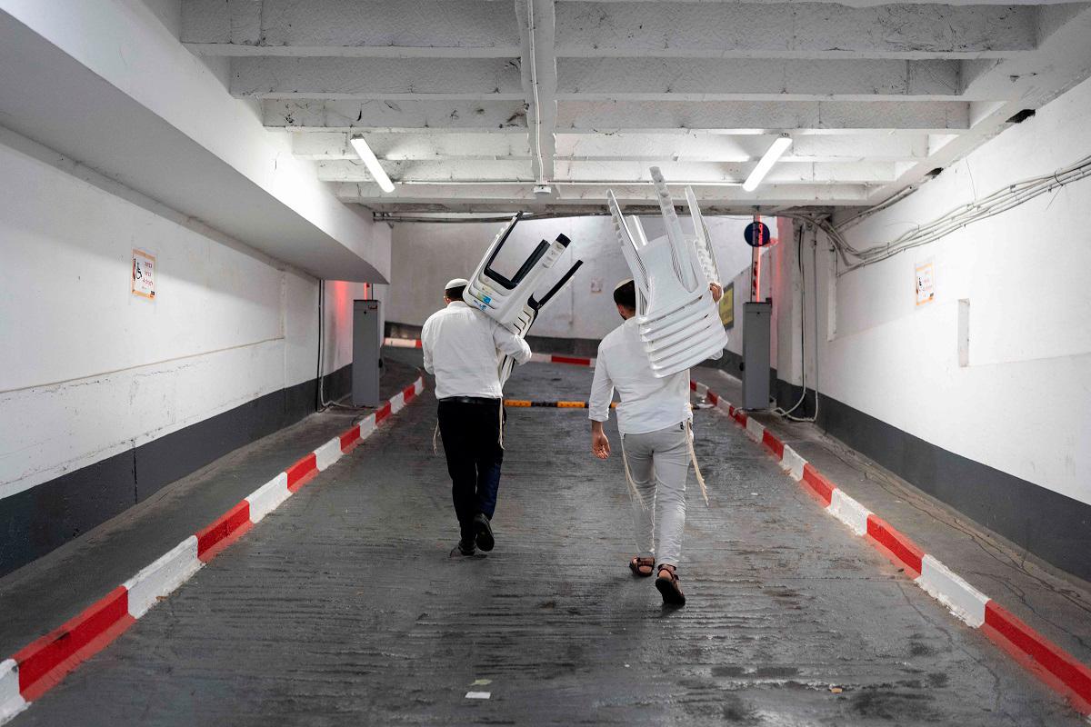 People take shelter in an underground parking lot under a mall in Tel Aviv, on June 21, 2025. Iran’s President Masoud Pezeshkian warned June 21, 2025 of a “more devastating” retaliation should Israel’s nine-day bombing campaign continue, saying the Islamic republic would not halt its nuclear programme “under any circumstances”. - Maya Levin / AFP