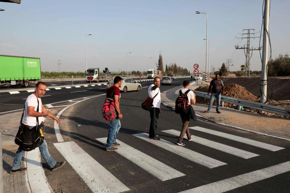 A picture taken from the Israeli side of Tarkumiya checkpoint near the southern city of Kiryat Gat, shows Palestinian workers crossing into Israel to reach their jobs on Nov 14. — AFP
