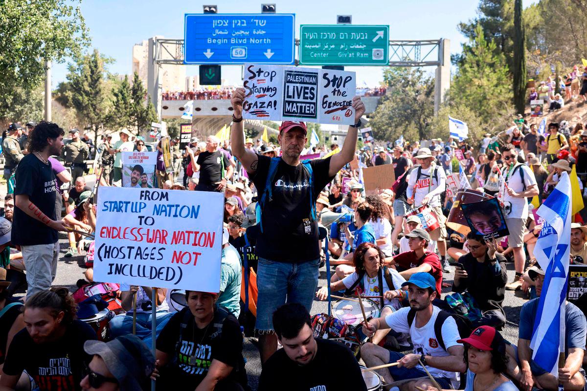 Families and supporters of Israelis held hostage by Hamas militants in Gaza since the October 7, 2023 attacks, hold placards and national flags during a protest calling for government action to secure their release in Jerusalem on August 17, 2025.(Photo by Menahem Kahana / AFP)