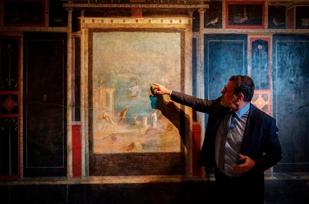 This undated photo handout on February 18, 2020 by the press office of the Archaeological Site of Pompeii shows a curator showing fresco in the “House of Orchards” during the reopening of three “domus” and conclusion of safety work on the archaeological site of Pompeii. AFP PHOTO / ARCHAEOLOGICAL SITE OF POMPEII