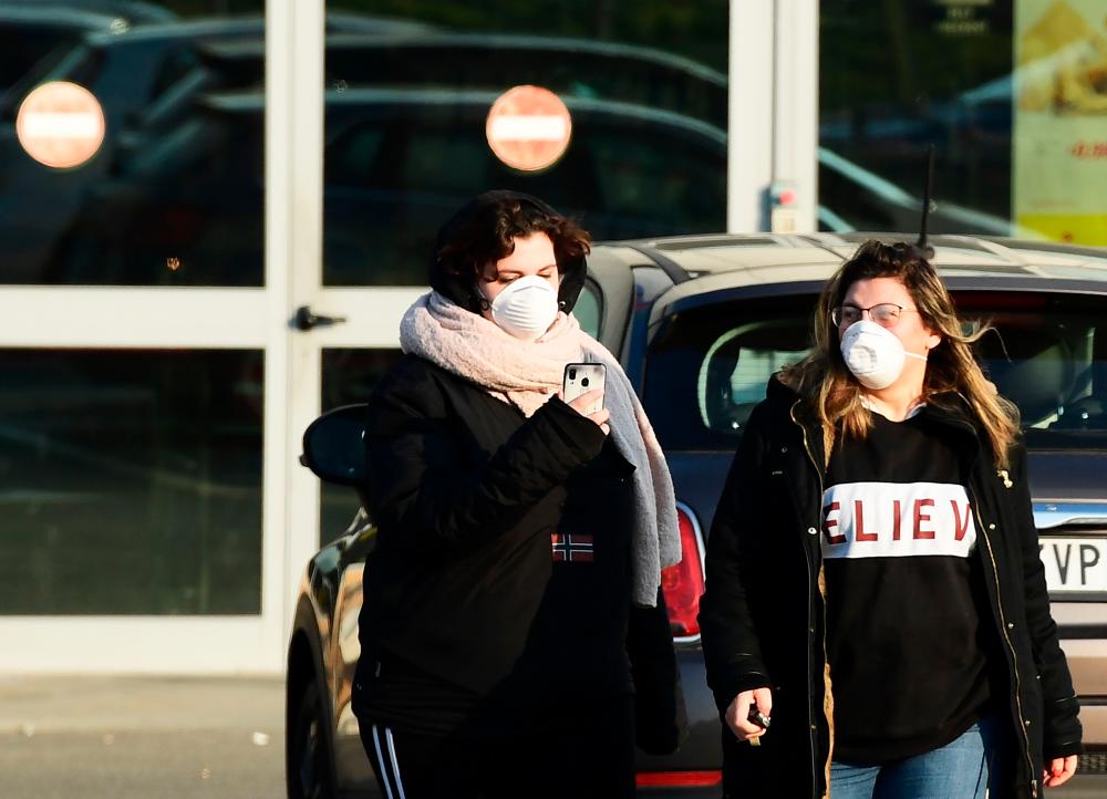 Women wearing a protective respiratory mask leave after finding out the local supermarket is closed in Codogno, southeast of Milan, on Feb 22. — AFP