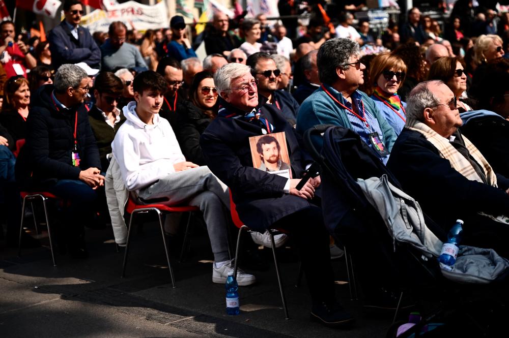 A family member of a mafia victim holds the photo of a murdered relative (C) during a demonstration on March 21, 2023 at Piazza Duomo in central Milan, to mark the 28th Memorial and Commitment Day in memory of the innocent victims of mafias, an initiative organised by the Libera association. AFPPIX