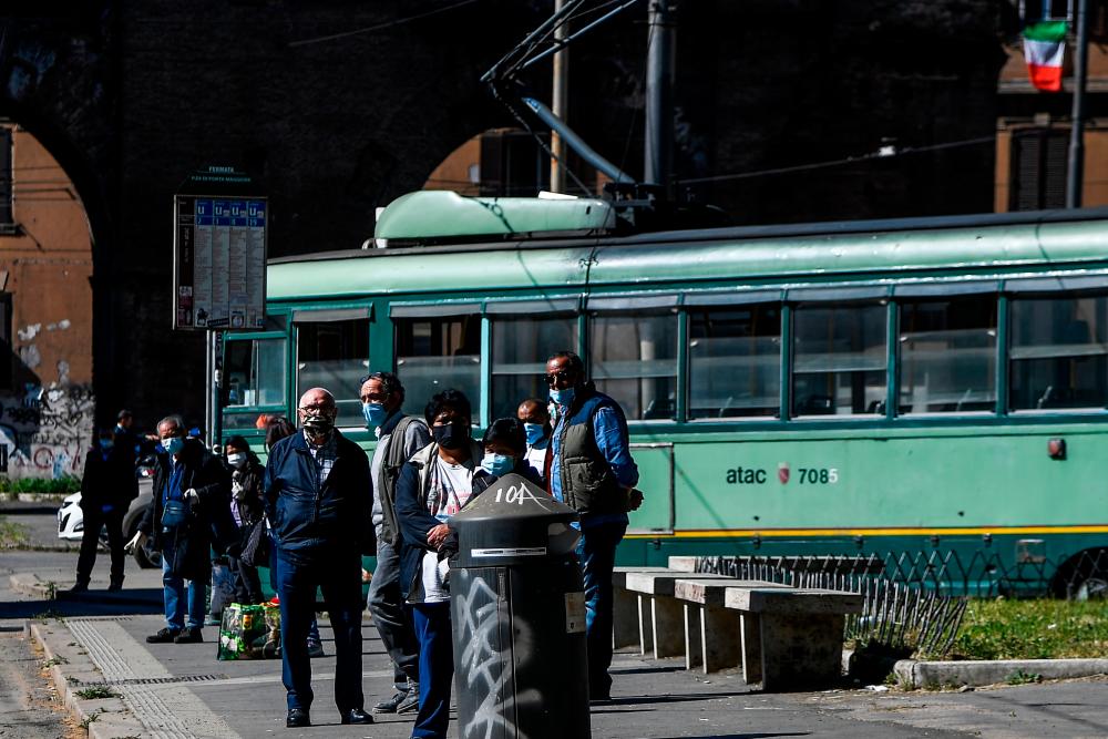 Commuters wait for the tramway at Porta Maggiore in Rome on May 4, 2020, as Italy starts to ease its lockdown, during the country's lockdown aimed at curbing the spread of the COVID-19 infection, caused by the novel coronavirus. — AFP