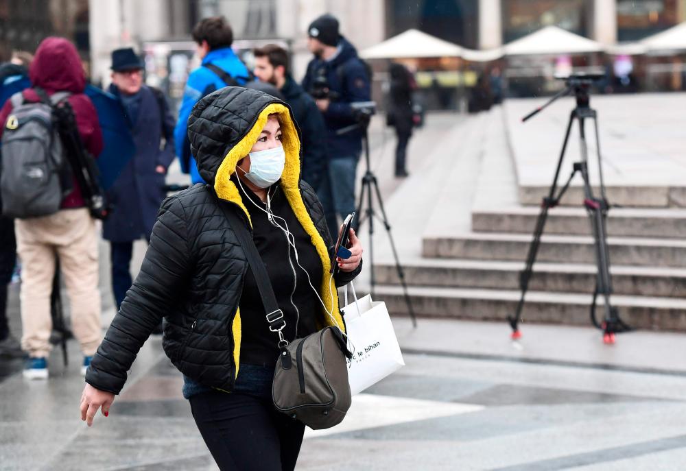 A woman wearing a protective face mask as a protection against the new Covid-19 coronavirus, walks in Piazza Duomo in Milan on Mar 2, 2020. — AFP