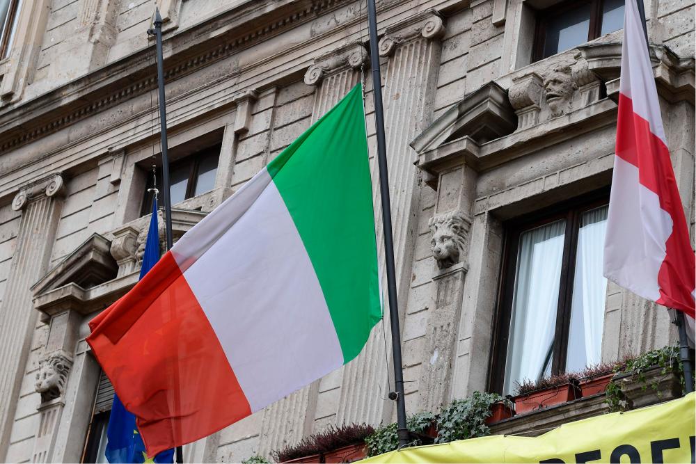 The Italian flag flies at half-mast on the city hall of Milan at noon on March 31, as flags are being flown at half-mast in cities across Italy to commemorate the victims of the virus, during the country's lockdown aimed at curbing the spread of the Covid-19 infection, caused by the novel coronavirus. - AFP