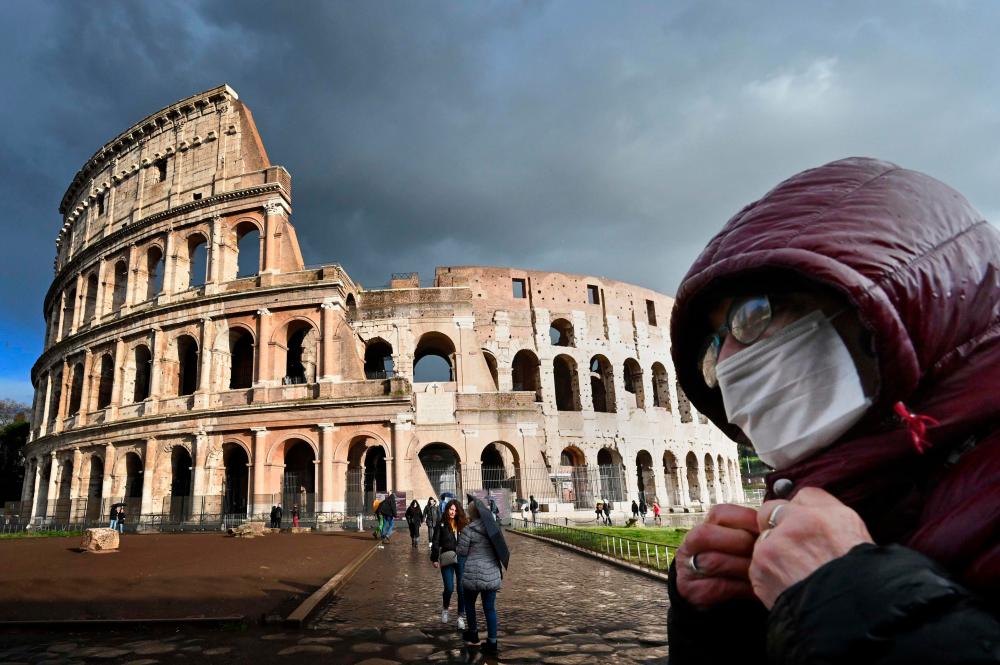 A man wearing a protective mask passes by the Coliseum in Rome on March 7, 2020 amid fear of Covid-19 epidemic. — AFP