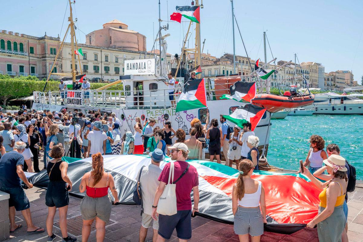 People gather around the Freedom Flotilla ship “Handala” ahead of the boat’s departure for Gaza at a port in Syracuse, Sicily, southern Italy, on July 13, 2025. (Photo by Giovanni ISOLINO / AFP)