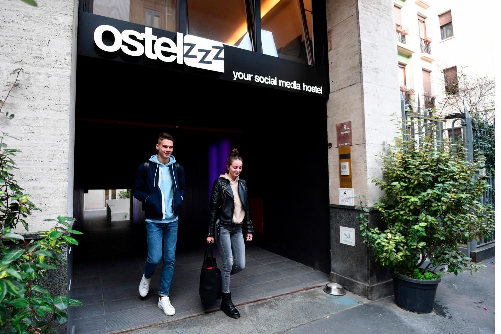 Guests walk out the new Ostelzzz capsule hotel in Milan on Oct 28. — AFP