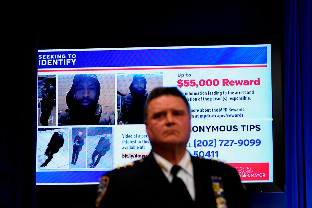 Reward information and photos of a person of interest are seen on a screen behind New York Police Chief of Detectives James Essig during a news conference about recent shootings of homeless people in both New York and Washington, at the John A. Wilson Building in Washington, U.S., March 14, 2022. REUTERSpix