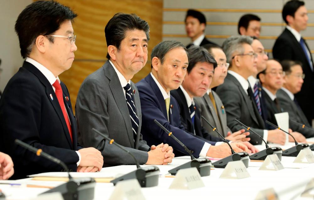 Japan's Prime Minister Shinzo Abe (2nd L) and Health Minister Katsunobu Kato (L) attend a meeting of the new Covid-19 coronavirus infectious disease control headquarters at the prime minister's office in Tokyo on February 14, 2020. - AFP