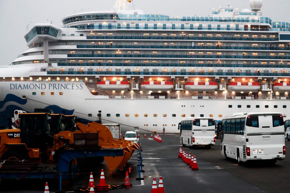 Two buses arrive next to the Diamond Princess cruise ship, with people quarantined onboard due to fears of the new coronavirus, at the Daikaku Pier Cruise Terminal in Yokohama port on February 16, 2020. - AFP