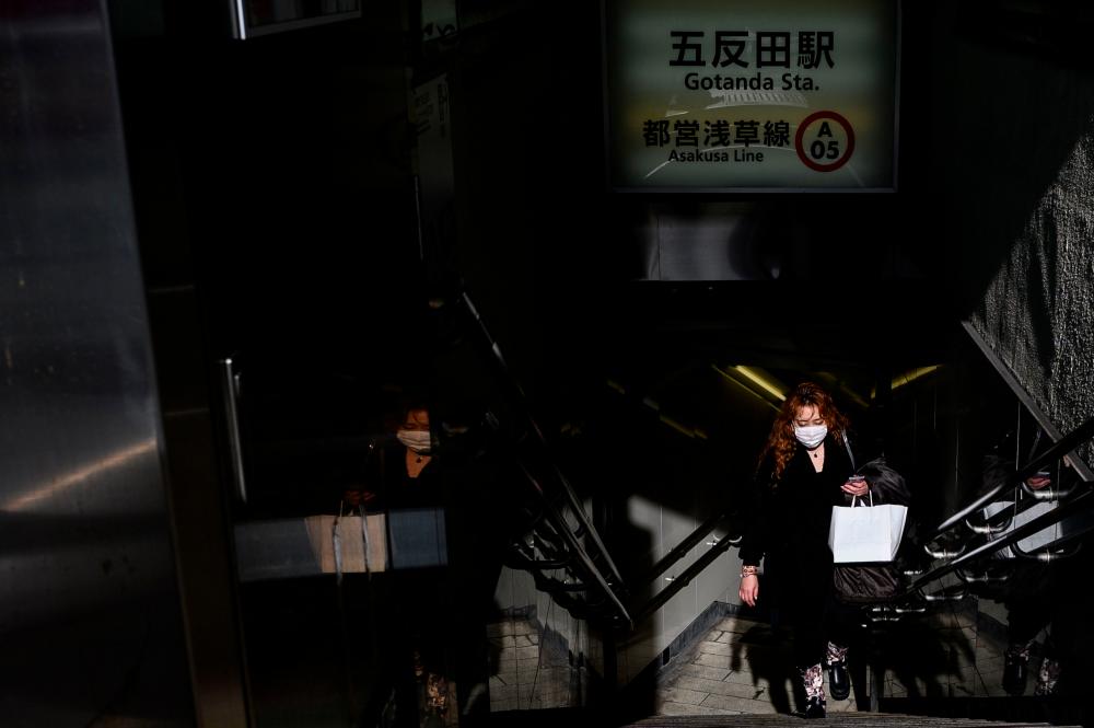 A woman wearing a face mask exits a subway station in Tokyo on Feb 22. — AFP