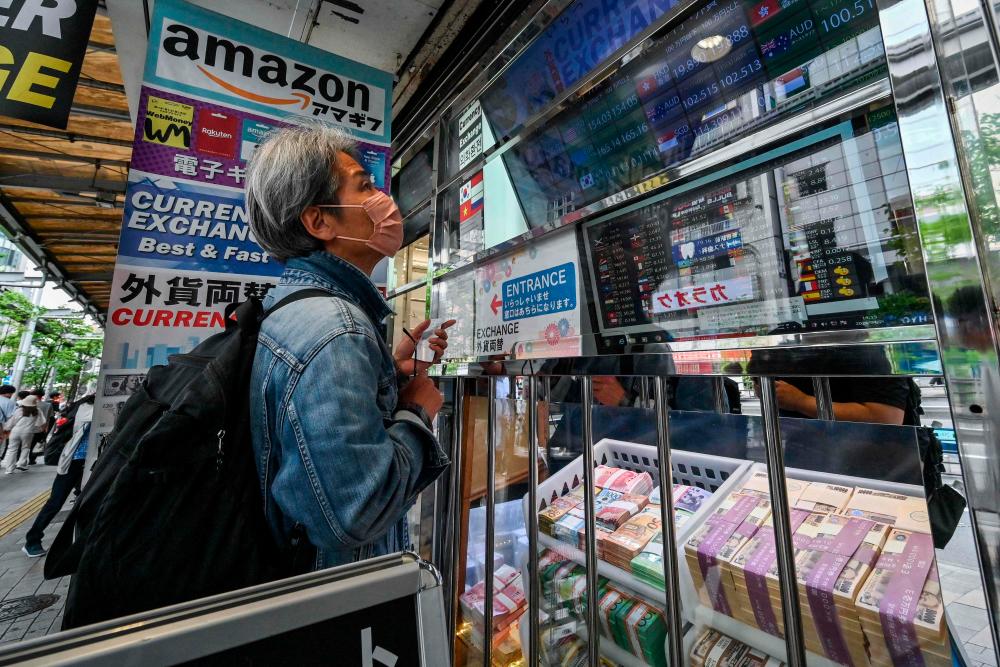 A man looks in the window of a money changer showing the rate of various currencies against the Japanese yen, along a street in central Tokyo on April 29, 2024/AFPPix