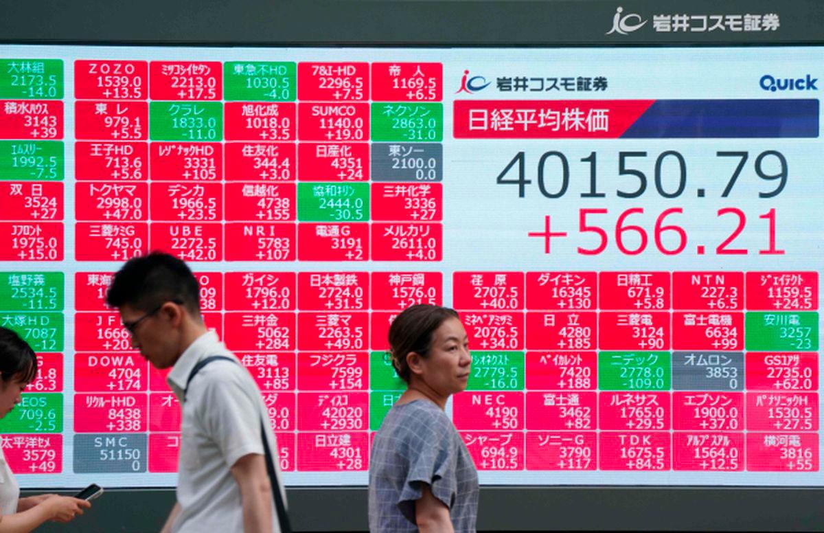 Pedestrians walk in front of an electronic quotation board displaying the Nikkei Stock Average closing price at 40,000 yen level on the Tokyo Stock Exchange in Tokyo on June 27, 2025. - AFPPIX