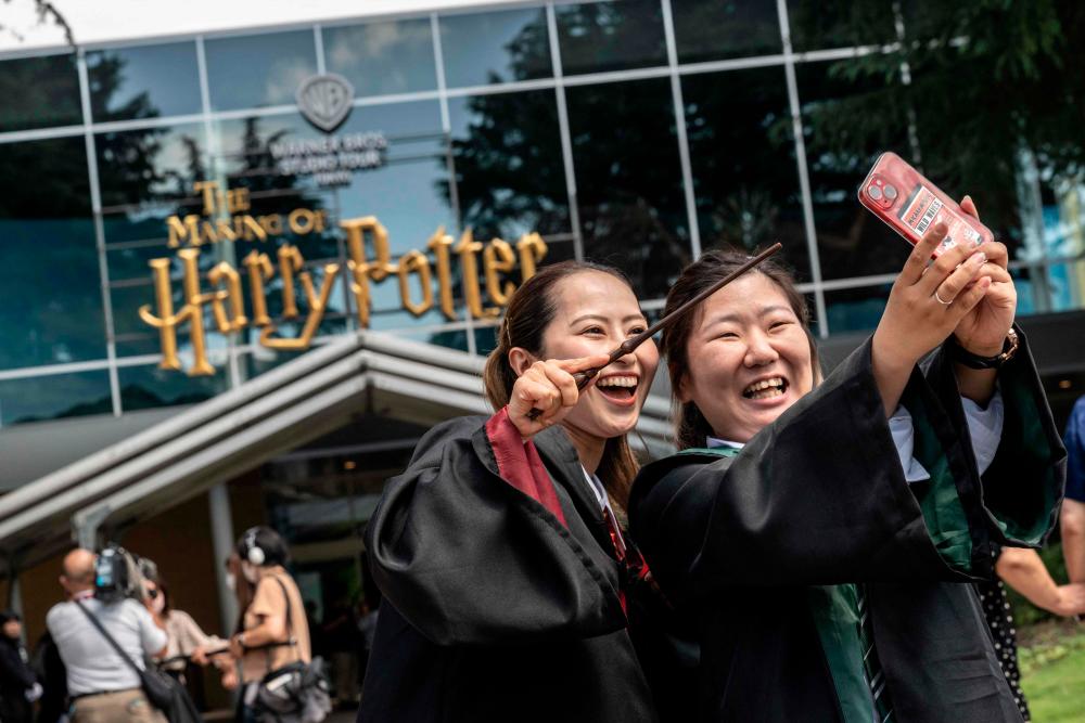 People wearing costumes pose for photographs in front of the entrance of the theme park “Warner Bros. Studio Tour Tokyo - The Making of Harry Potter” in Tokyo on June 16, 2023. AFPPIX