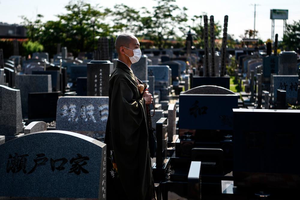 This photo taken on June 16, 2020 shows Yogetse Akasaka, a Buddhist monk and beatbox musician, posing at a cemetery after a religious ceremony in Shimoshizu, Chiba prefecture. / AFP / CHARLY TRIBALLEAU /