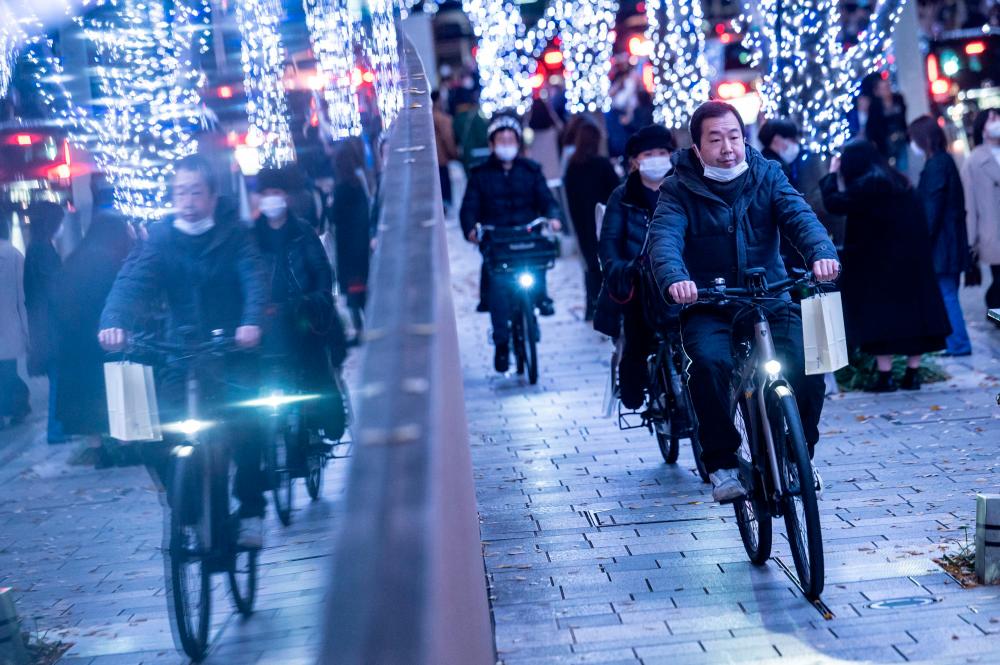 Cyclists are seen in the Roppongi area of Tokyo on Sunday. Price inflation pushed Japanese real wage growth into negative territory for the seventh consecutive month. – AFPpic