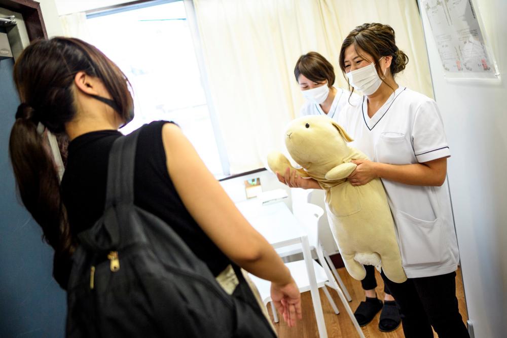 $!This photo taken on September 13, 2020 shows client Yui Kato (L) greeting her stuffed toy sheep Yuki-chan (C) and founder Natsumi Hakozaki (R) at Natsumi Clinic in Tokyo. AFP / Philip FONG