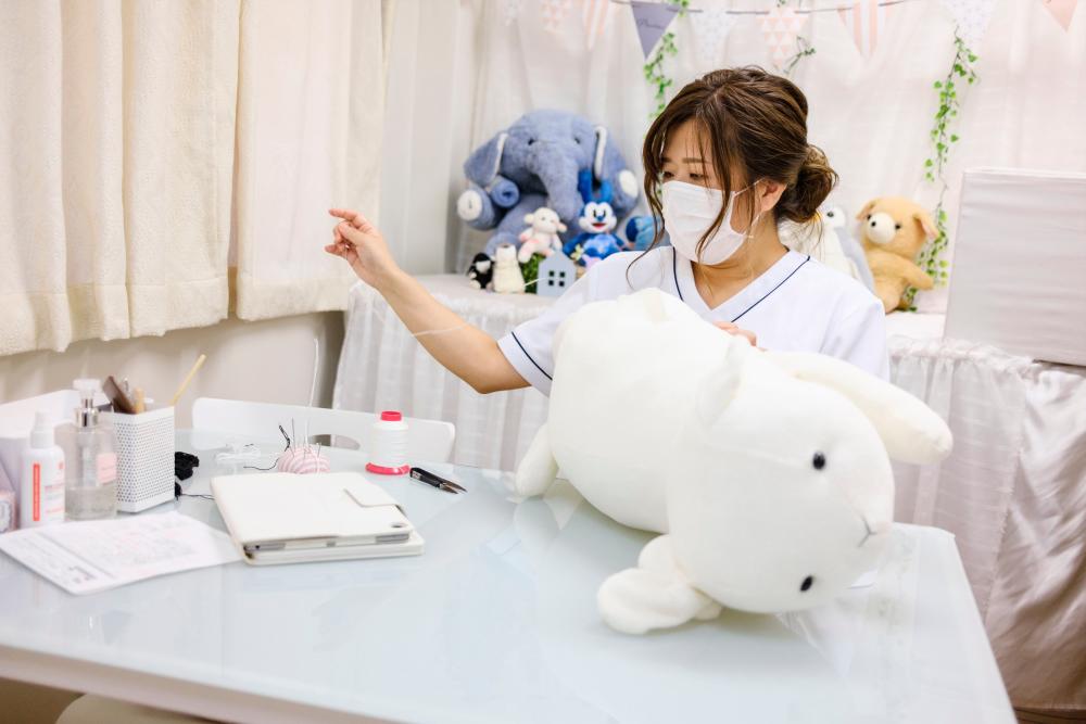 This photo taken on September 18, 2020 shows founder Natsumi Hakozaki working on client Yui Kato’s stuffed toy sheep Yuki-chan at Natsumi Clinic in Toyko. AFP / Philip FONG