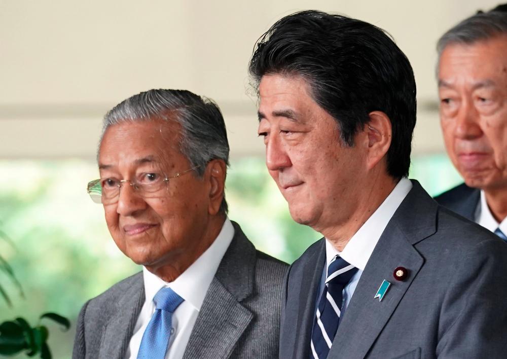 Prime Minister Tun Dr Mahathir Mohamad (L) walks with Japan's Prime Minister Shinzo Abe (R) after their meeting at Abe's official residence in Tokyo on May 31, 2019. - AFP