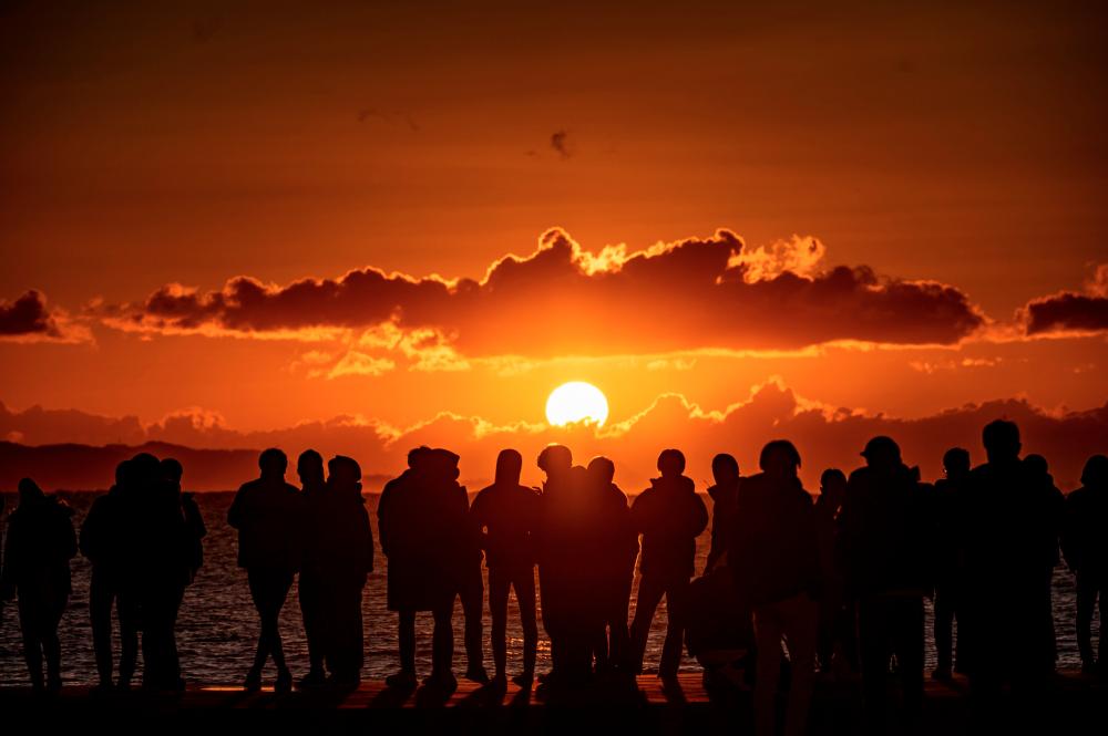People gather at Southern Beach of Chigasaki to watch the sunrise on New Year’s Day in Kanagawa Prefecture, southwest of Tokyo on January 1, 2021. / AFP / Philip FONG