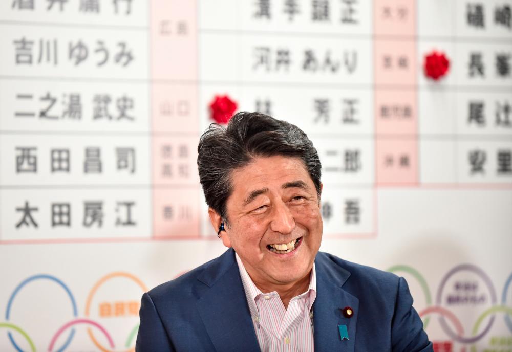 Japanese Prime Minister and ruling Liberal Democratic Party (LDP) president Shinzo Abe smiles as he responds to questions during a television interview following the Parliament's upper house election at the party's headquarters in Tokyo on July 21, 2019. — AFP