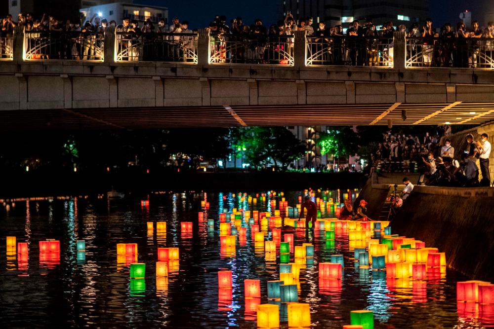 People watch paper lanterns floating on the Motoyasu River beside the Hiroshima Prefectural Industrial Promotion Hall, commonly known as the atomic bomb dome, to mark the 77th anniversary of the world’s first atomic bomb attack in Hiroshima/AFPPix