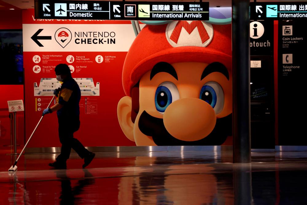 A cleaner mops the floor in front of a Nintendo’s Super Mario game character decoration at Narita Airport in China prefecture on June 1, 2021. – AFP