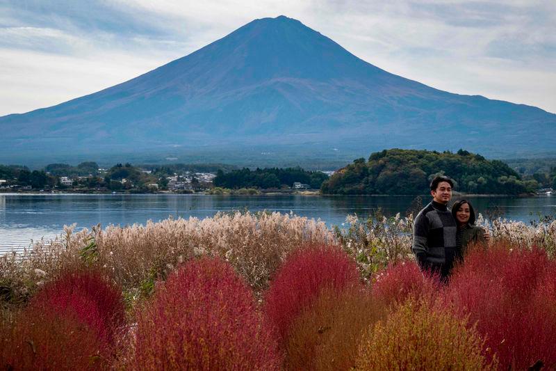 People take photographs before Mount Fuji, the highest mountain in Japan at 3,776 metres (12,460 feet), in Fujikawaguchiko, Yamanashi prefecture - AFPpix