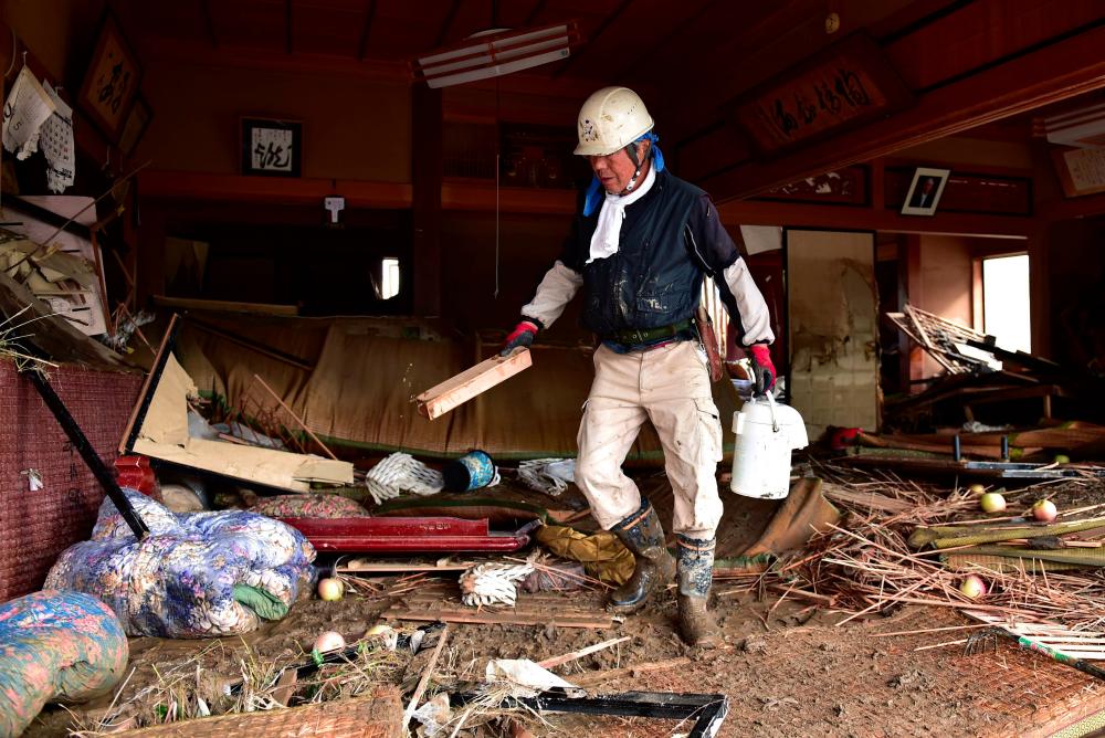 A resident cleans a flood-damaged home in Nagano on Oct 15, 2019, after Typhoon Hagibis hit Japan on Oct 12, unleashing high winds, torrential rain and triggered landslides and catastrophic flooding. — AFP