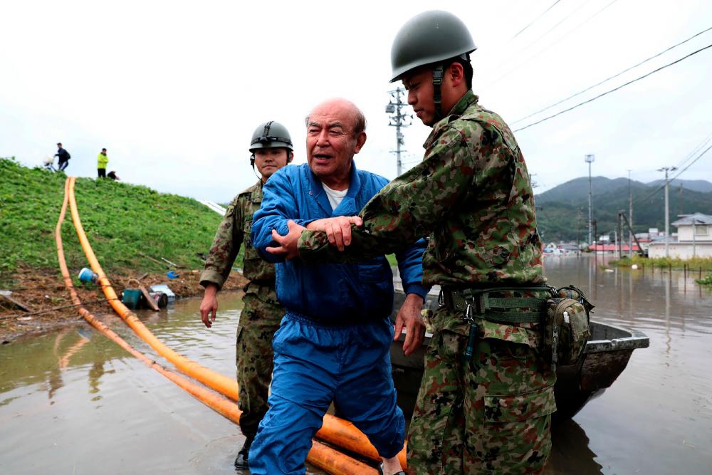 Japan Self-Defense Forces evacuate a man from a flooded area during search and rescue operations in the aftermath of Typhoon Hagibis in Marumori, Miyagi prefecture on Oct 14, 2019. — AFP