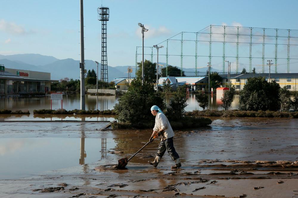 A resident removes mud from an area which was flooded by Typhoon Hagibis in Nagano on Oct 16, 2019. — AFP