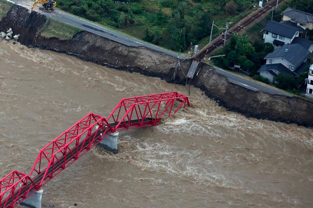 This aerial view shows a damaged train bridge over the swollen Chikuma river in the aftermath of Typhoon Hagibis in Ueda, Nagano prefecture on Oct 13, 2019. — AFP
