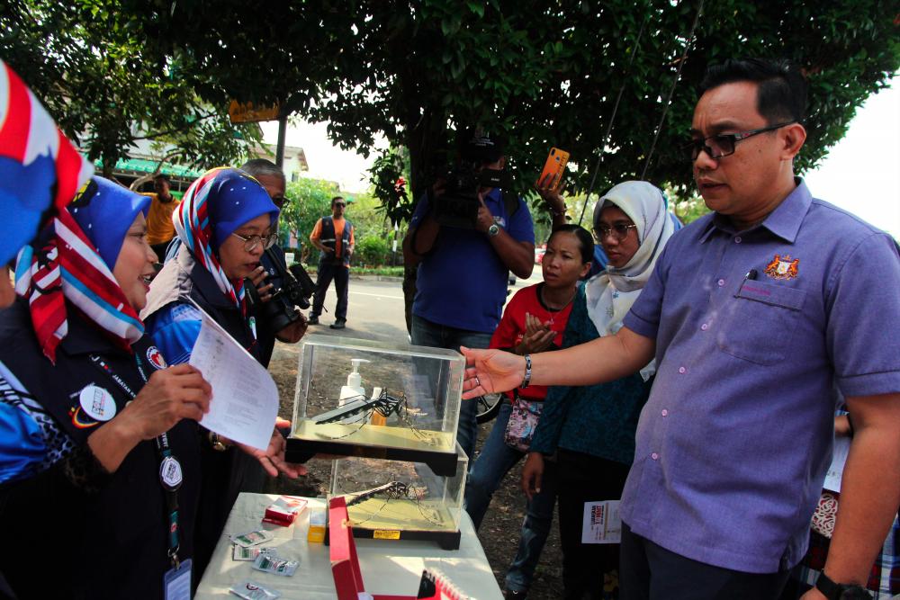 Johor State Department of Health personnel described the Aedes mosquito species to Johor Health, Culture and Heritage Committee chairman Mohd Khuzzan Abu Bakar (R) during the Individual Premises Enforcement Operation (OPPI) at the dengue outbreak area in Taman Damai Jaya, Skudai. - Bernama
