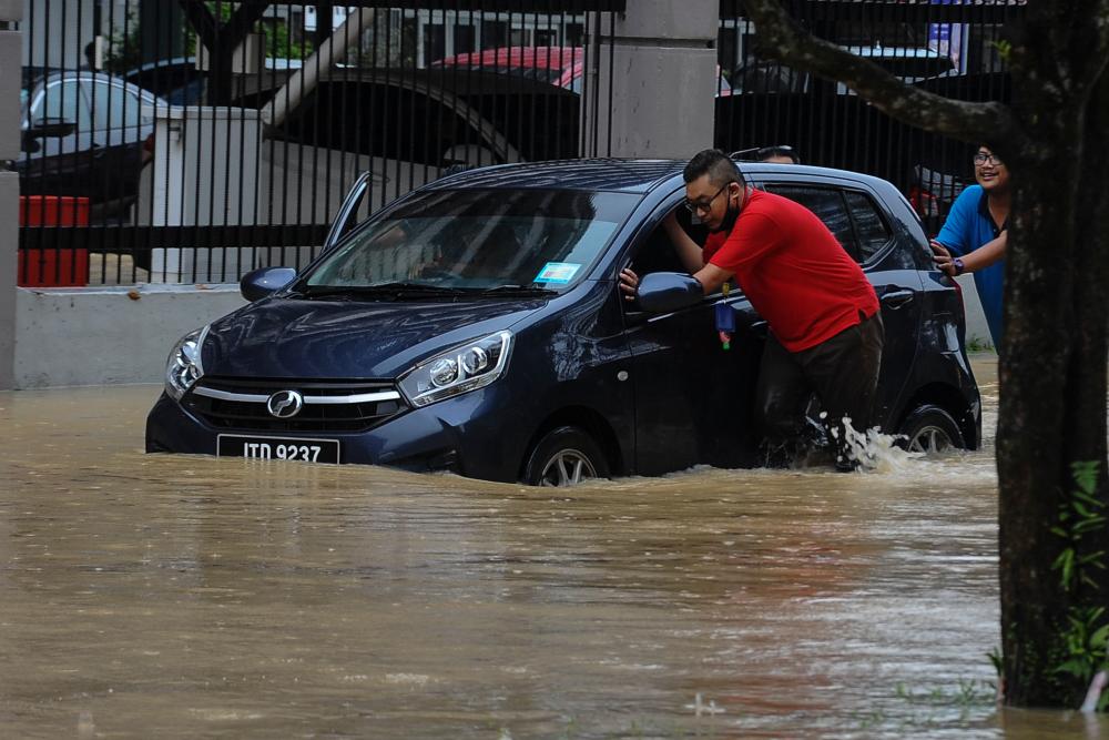 JOHOR BAHRU, 2 August -- Some vehicle owners on Jalan Ayer Molek pushed their vehicles that were flooded following the flash flood for several hours in the city of Johor Bahru today. BERNAMAPIX