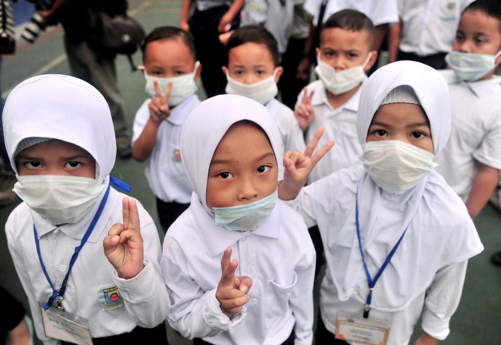 The Sekolah Kebangsaan Taman Pasir Putih pupils wear masks during the assembly after the school reopened from a two-day holiday due to the smell of chemical spills at Sungai Kim, on March 11, 2019. — Bernama