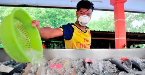 A worker wears a face mask while trading at the fisherman’s market in the South Johor Fishermen’s Association as a precautionary precaution against pollution. — Bernama