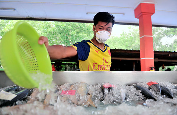 A worker wears a face mask while trading at the fisherman’s market in the South Johor Fishermen’s Association as a precautionary precaution against pollution. — Bernama