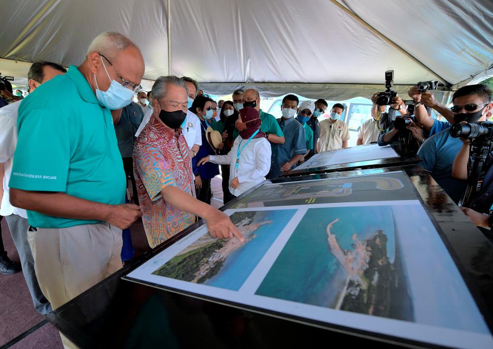 Prime Minister Tan Sri Muhyiddin Yassin inspects the Desaru Coast ferry terminal development project plan under construction, while being briefed by General Manager of Marine Operations Desaru Coast Sathasivam N. K. (L) during a working visit to Desaru Coast, Kota Tinggi today. - Bernama