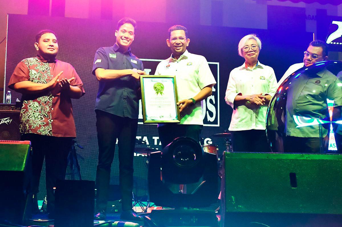 Ahli Dewan Undangan Negeri (ADUN) Parit Yaani (tengah) menerima sijil pengiktirafan Malaysia Book of Records (MBOR) daripada wakil rasmi MBOR, Megat Farish Hussein Megat Muzaffar Shah (dua, kiri) pada Program Jelajah Orang Johor (JOJ) yang diadakan di kawasan parkir sebuah pasar raya malam tadi. - BERNAMA