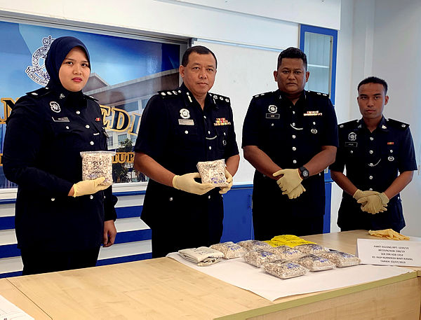Batu Pahat district police chief ACP Azhan Abdul Halim (2nd from L) displays the heroin that was seized in a parking lot of a supermarket in Parit Sulong on July 3, at around 10.30am, involving five suspects, worth RM63,000, at a press conference at the Batu Pahat District Police Headquarters today. — Bernama