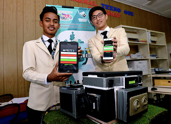 Project leader, Muhammad Amir Hariz Mashuri, 16, and one of his teammates Teo Jun Jet, 14 from SMK Tun Habab presenting their smartphone application that controls their invention, the portable air conditioner ‘Peltz’