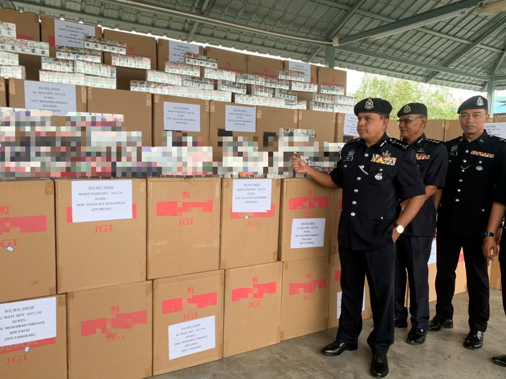 Johor police chief Datuk Ayob Khan Mydin Pitchay (3rd from R) displays some of the seized cigarettes worth a total of RM3.2 million, at a press conference at the Muar PPM base today. - Bernama