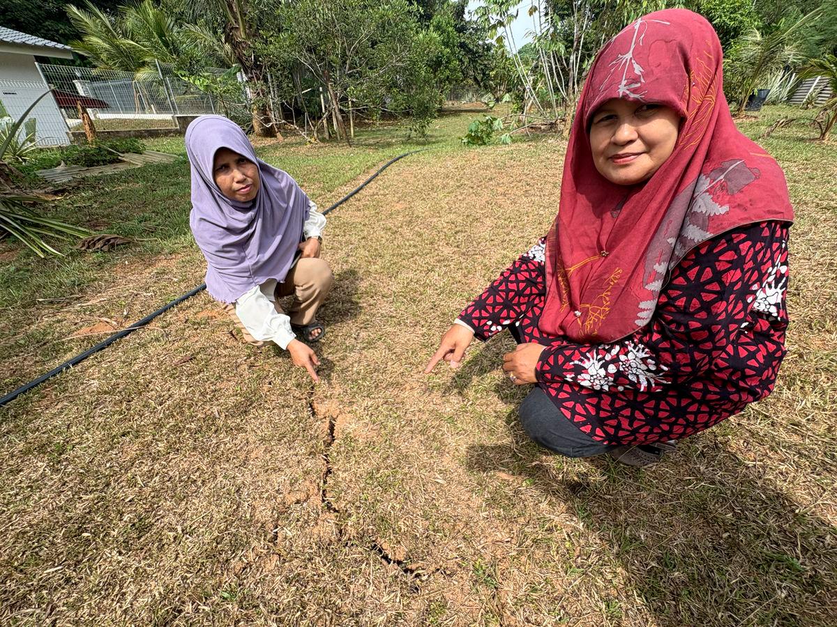 Penduduk Jalan Buloh Kasap, Batu 2 Ramlah Ishak, 56, (kiri) bersama kakaknya Umi Kalsom Ishak, 58, menunjukkan kesan rekahan tanah ketara di kawasan kebun di bahagian belakang rumah yang dipercayai berpunca daripada gegaran gempa bumi ketika ditemui Bernama, di sini hari ini- fotoBERNAMA