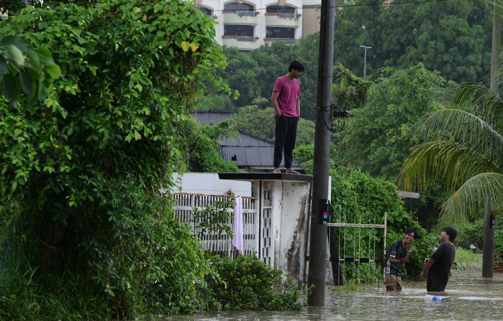 JOHOR BAHRU, 25 Sept -- Gelagat beberapa pelajar Netherlands Maritime University College (NMUC) ketika meredah banjir di Kampung Mohd Amin ekoran hujan lebat berterusan sejak pagi tadi. - BERNAMAPIX