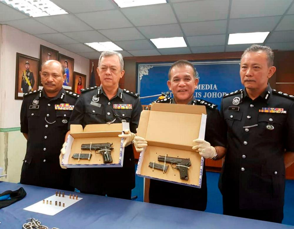 Johor police deputy chief Datuk Shafie Ismail (2nd from R) and SAC Johor CID chief Md Yusof Ahmad (2nd from L) display two pistols seized as a result of PDRM rescuing a businessman who had been kidnapped since last week after shooting dead two criminals at an oil palm plantation in Mersing, earlier this morning, at a press conference at the Johor contingent police headquarters today. - Bernama