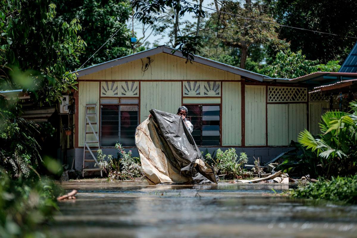 Seorang penduduk, Aileen Hana Abdullah mengemas sekitar luar rumahnya yang dinaiki air ketika tinjauan fotoBernama di Kampung Paya Embun, Pekan Nenas hari ini. - fotoBERNAMA