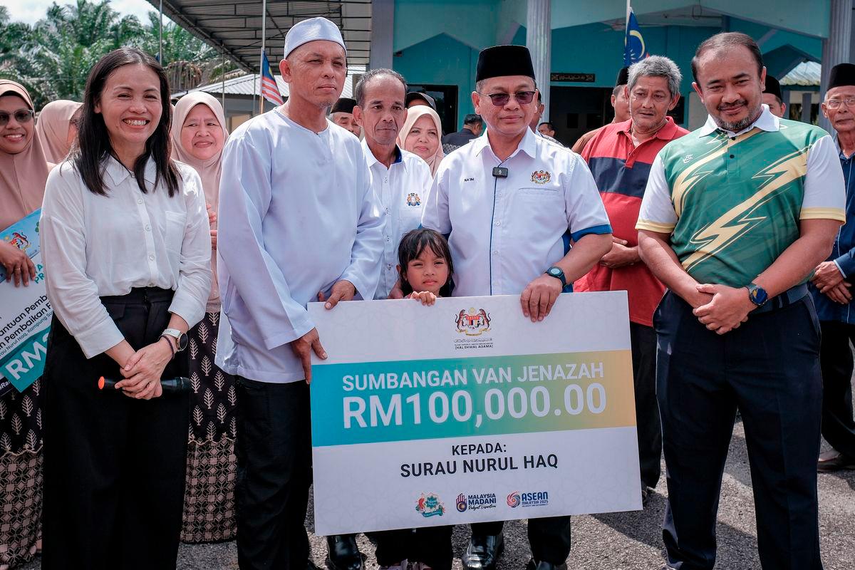 Menteri di Jabatan Perdana Menteri (Hal Ehwal Agama) Datuk Dr Mohd Na'im Mokhtar (tiga, kanan) diiringi Timbalan Menteri Komunikasi yang juga Ahli Parlimen Kulai Teo Nie Ching (dua, kiri) menyerahkan replika cek sebanyak RM100,000 kepada Pengerusi Surau Nurul Haq Kampung Sungai Sayong 1 Mohd Anuar Repan (tiga, kiri) bagi tujuan pembelian semula van jenazah yang dicuri baru-baru ini di Kampung Sungai Sayong hari ini. - BERNAMA